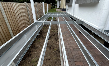 Silver subframe structure in between the side of a house and a fence