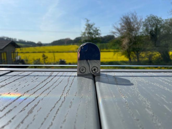 D clamp on a glass and pvc decking with a view of fyellow flowers and blue sky